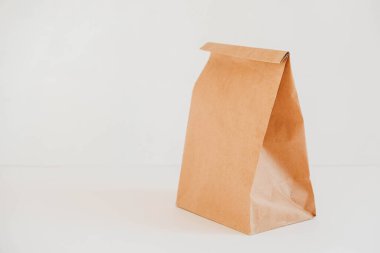 Beyaz arka planda kahverengi kraft kağıdından yapılmış tek kullanımlık paket. Kopyala, metin için boşluk.