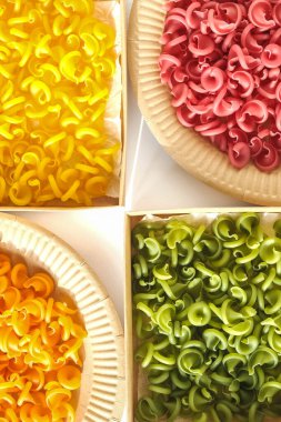 Tek kullanımlık kağıt tabaklarda çok renkli makarna ve beyaz arka planda kutular. Üst Manzara. Kopyala, metin için boşluk.