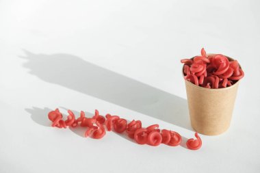 Beyaz arka planda tek kullanımlık kağıt bardakta kırmızı makarna. Kopyala, metin için boşluk.