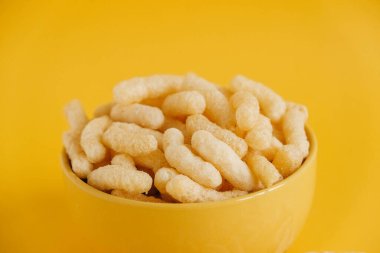 Sarı arka planda sarı bir kasede mısır çubukları. Kopyala, metin için boşluk.