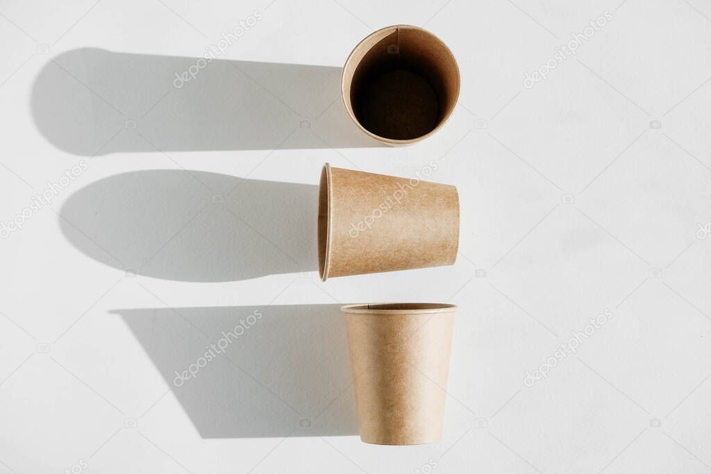 Three disposable paper cup with shadow from light on a white background. Top view. Copy, empty space for text.