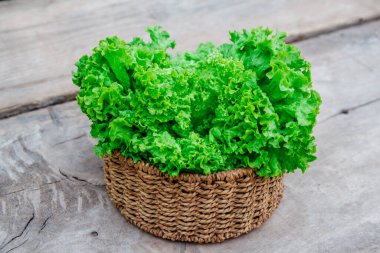 Tahta bir arka planda sepetin içindeki yeşil lahana yapraklarını kapat..