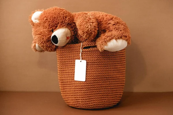 Toy teddy bear with a knitted bag on a brown background. Copy, empty space for text.