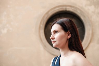 Eski duvarın arkasında elbise giymiş güzel bir kadının portresi. Kopyala, metin için boşluk.