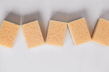 Beyaz arka planda sarı gözenekli süngerler. Üst Manzara. Kopyala, metin için boşluk.