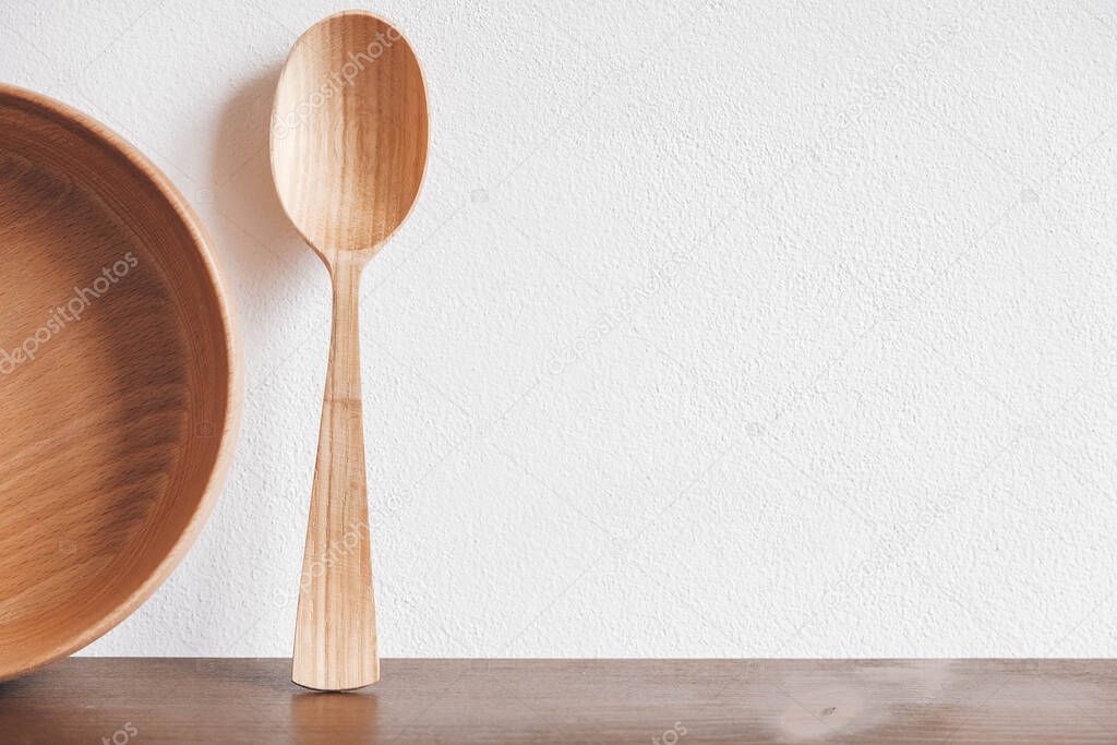 Empty wooden bowl and wooden spoon on a brown table background. Copy, empty space for text.