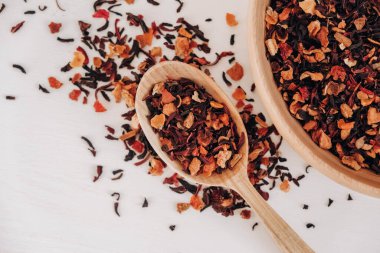 Beyaz arka plana saçılmış tahta bir kaşıkta kurumuş meyve çayı. Üst Manzara. Kopyala, metin için boşluk.