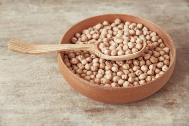 Ahşap bir tabakta çiğ nohut ve ahşap bir arka planda kaşık. Üst Manzara. Kopyala, metin için boşluk.