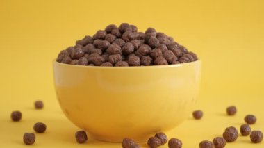 Sarı arka planda sarı bir kasede çikolatalı mısır topları. Kahvaltı konsepti.