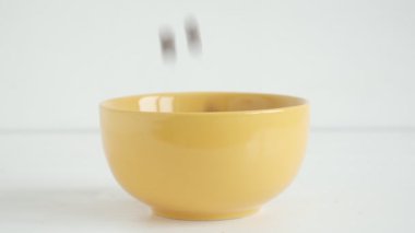 Beyaz arka planda sarı bir kaseye düşen çikolatalı mısır topları. Kahvaltı konsepti.