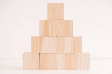 Tahta bloklar piramidi beyaz arka planda doğal ahşaptan. Kopyala, metin için boşluk.