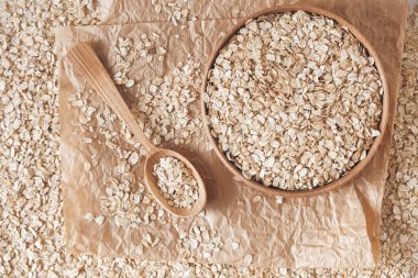 Tahta bir kâsede pişmemiş yulaf ezmesi ve kese kağıdında kaşık. Üst Manzara. Kopyala, metin için boşluk.