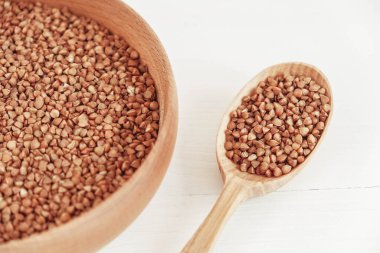 Tahta kasede karabuğday taneleri ve beyaz arka planda kaşık. Üst Manzara. Kopyala, metin için boşluk.