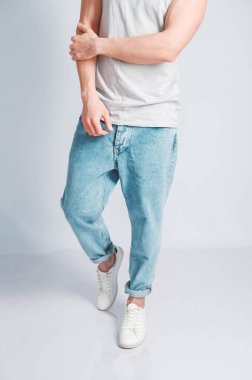 Açık tişörtlü, beyaz arka planda kot pantolonlu, kaslı genç bir adam. Kopyala, metin için boşluk.