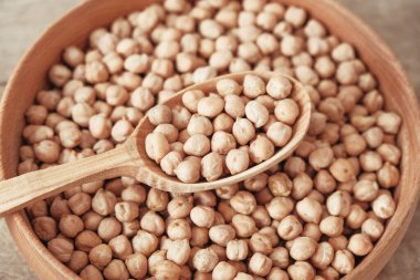 Ahşap bir tabakta çiğ nohut ve ahşap bir arka planda kaşık. Üst Manzara. Kopyala, metin için boşluk.