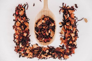 Beyaz arka plana saçılmış tahta bir kaşıkta kurumuş meyve çayı. Üst Manzara. Kopyala, metin için boşluk.