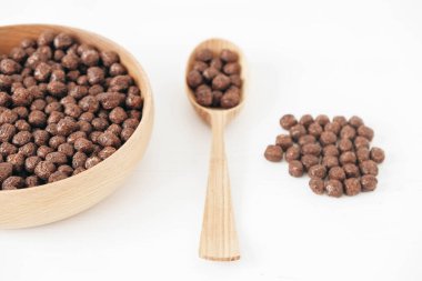 Tahta bir kasede çikolatalı mısır topları ve beyaz bir arka planda kaşık. Üst Manzara. Kopyala, metin için boşluk.