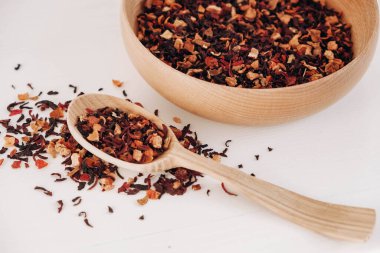 Beyaz arka plana saçılmış tahta bir kaşıkta kurumuş meyve çayı. Üst Manzara. Kopyala, metin için boşluk.