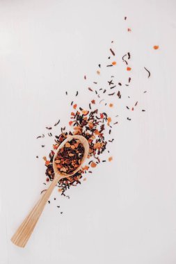 Beyaz arka plana saçılmış tahta bir kaşıkta kurumuş meyve çayı. Üst Manzara. Kopyala, metin için boşluk.