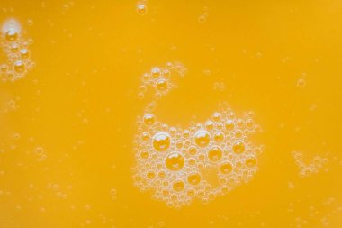 Arkaplan dokusu olarak sarı bir sıvının yüzeyindeki kabarcıklar. Üst Manzara. Kopyala, metin için boşluk