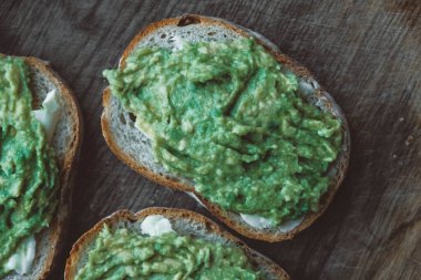 Ahşap zemin üzerinde avokado bulunan çavdar ekmeği dilimleri, basit bir köy sandviçi. Üst Manzara. Kopyala, metin için boşluk.