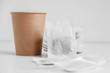 Kağıt bardak ve beyaz arka planda çay poşetleri. Kopyala, metin için boşluk.