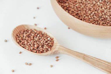 Tahta kasede karabuğday taneleri ve beyaz arka planda kaşık. Üst Manzara. Kopyala, metin için boşluk.