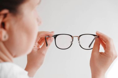 Siyah çerçeveli, beyaz arka planda optik gözlük tutan bir kadın. Kopyala, boşluk.
