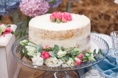 Çiçeklerle süslenmiş beyaz düğün pastası şenlik masasında duruyor. Kopyala, metin için boşluk.