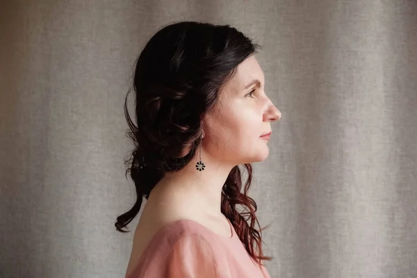Porträt einer brünetten Frau in einem rosa Kleid auf einem Leinenhintergrund. Kopieren, leerer Raum für Text — Stockfoto