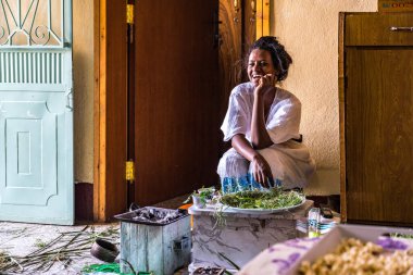 Axum, Etiyopya - 9 Şubat 2020: Geleneksel giysiler içinde genç bir kadın bir kahve seremonisi hazırlıyor. Bu tören Etiyopya kültürünün önemli bir parçasıdır..