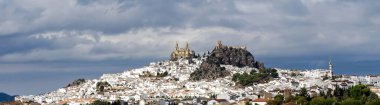 View of Olvera village, one of the beautiful white villages, Pueblos Blancos of Andalucia, Spain. It features a moorish fortress and a neoclassic cathedral overlooking the whitewashed village. clipart
