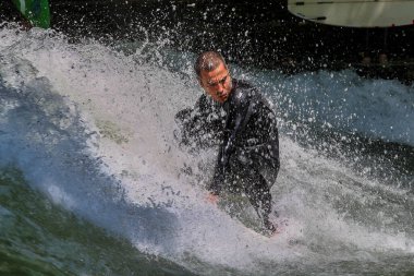 Münih, Almanya - 13 Temmuz 2019: Münih şehir nehrinde sörfçü, Eisbach adı verilen kentsel çevrede sörf yapan insanlarla ünlüdür.