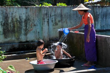 Mandalay, Myanmar - 09 Kasım 2019: Birmanyalı anne Mandalay, Myanmar 'da çocuklarını suyla yıkıyor.
