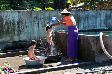 Mandalay, Myanmar - 09 Kasım 2019: Birmanyalı anne Mandalay, Myanmar 'da çocuklarını suyla yıkıyor.