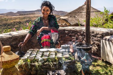 Lalibela, Etiyopya - 13 Şubat 2020: Geleneksel giysili genç kadın bir kahve seremonisi hazırlıyor. Bu tören Etiyopya kültürünün önemli bir parçasıdır..