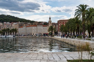 Split, Hırvatistan - 22 Haziran 2020: Splitska Riva Gezinti Alanı ve liman ile Hırvatistan 'ın Split kentindeki Diocletian sarayı arasında palmiye ağaçları bulunuyor