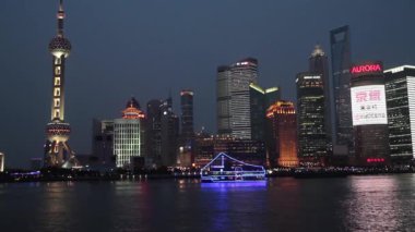 Arka planda Pudong bölgesi ile Şangay 'daki Huangpu nehri üzerinde bir tur teknesi. Pudong bölgesinde Lujiazui Finans ve Ticaret Bölgesi ve Şangay Borsası bulunmaktadır..