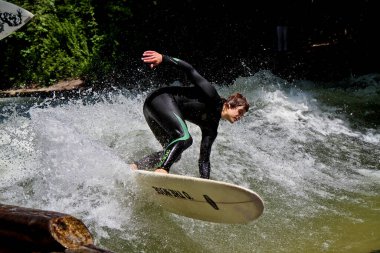 Münih, Almanya - 13 Temmuz 2019: Münih şehir nehrinde sörfçü, Eisbach adı verilen kentsel çevrede sörf yapan insanlarla ünlüdür.