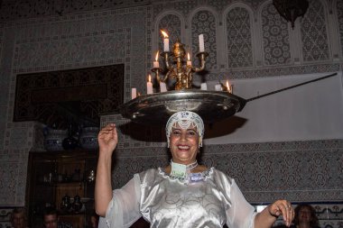 Marakeş, Fas - 22 Ekim 2019: Marakeş, Fas 'ta Dar Es-Salam adlı bir restoranda geleneksel halk müziği eşliğinde dans eden bir kadın sanatçı.