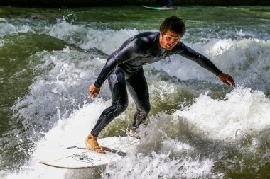 Münih, Almanya - 13 Temmuz 2019: Münih şehir nehrinde sörfçü, Eisbach adı verilen kentsel çevrede sörf yapan insanlarla ünlüdür.