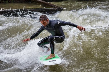 Münih, Almanya - 13 Temmuz 2019: Münih şehir nehrinde sörfçü, Eisbach adı verilen kentsel çevrede sörf yapan insanlarla ünlüdür.