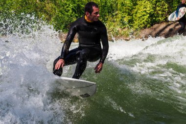 Münih, Almanya - 13 Temmuz 2019: Münih şehir nehrinde sörfçü, Eisbach adı verilen kentsel çevrede sörf yapan insanlarla ünlüdür.