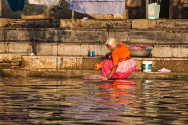 Udaipur, Hindistan - Ocak 03, 2020: Kimliği belirsiz Hintli kadın Pichola Gölü 'nde çamaşır yıkıyor. Çamaşır yıkamak Hindistan 'da yaygındır..
