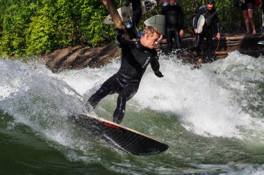 Münih, Almanya - 05 Temmuz 2021: Münih şehir nehrinde sörfçü Eisbach adı verilen kentsel çevrede sörf yapan insanlarla ünlüdür.
