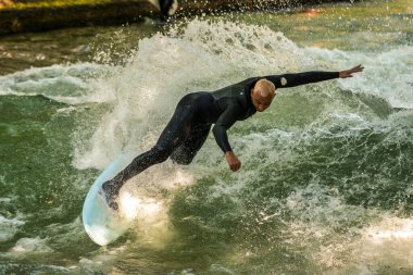 Münih, Almanya - 13 Temmuz 2021: Münih şehir nehrinde sörfçü, Eisbach adı verilen kentsel çevrede sörf yapan insanlarla ünlüdür.