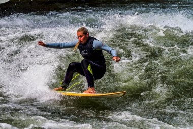 Münih, Almanya - 13 Temmuz 2021: Münih şehir nehrinde sörfçü, Eisbach adı verilen kentsel çevrede sörf yapan insanlarla ünlüdür.