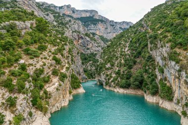 Turistler, güneşli bir yaz gününde Fransa 'daki Verdon Gorge Nehri' nin turkuaz sularında pedal çeviren ve kano kullanan turistler.
