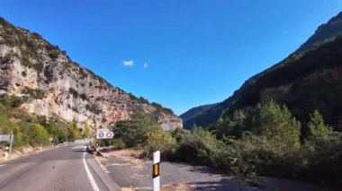 Driving through the landscape between Ainsa and Broto, showing dramatic cliffs, dense forests, and misty peaks of Ordesa Valley in the Pyrenees, Aragon, Spain.