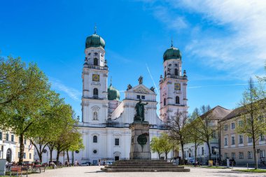 Passau, Almanya - 16 Nisan 2025: Passau, Almanya 'daki St. Stephans Katedrali kulelerin tepesinde yeşil metal kubbeler bulunan eski bir beyaz kilisedir. Kilisenin önünde Maximillian Joseph 'in heykeli var.